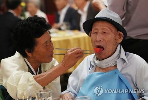 资料图片：8月20日下午，第一轮韩朝离散家属团聚活动在朝鲜金刚山酒店举行，图为朝方女儿（70岁，左）在晚宴上给百岁的韩方父亲喂饭。（韩联社） 