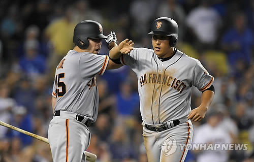 In this Associated Press photo taken on July 28, 2017, Hwang Jae-gyun of the San Francisco Giants (R) is congratulated by Matt Moore after scoring a run against the Los Angeles Dodgers in the teams' Major League Baseball game at Dodger Stadium in Los Angeles. (Yonhap)