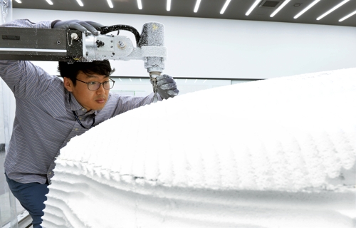 An employee of Hyundai Mobis works on a design sample for auto parts with the help of a clay model processing machine at the company's design center in Yongin, Gyeonggi Province. (Photo courtesy of Hyundai Mobis) (Yonhap)