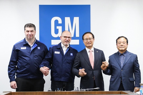 In this photo taken April 23, 2018, (from L to R) GM Korea President and Chief Executive Kaher Kazem, GM Executive Vice President Barry Engle, ruling Democratic Party lawmaker Hong Young-pyo and Moon Seung, who represents 140,000 workers at GM Korea's subcontractors, hold hands after the company and its union reached a tentative restructuring agreement at the main Bupyeong plant, just west of Seoul. (Yonhap)