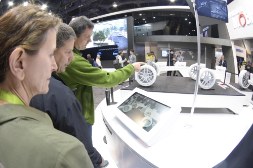 In this photo taken at the Consumer Electronics Show in Las Vegas in January, officials from a carmaker look around next-generation car technologies displayed at Hyundai Mobis' booth. (Yonhap)