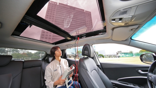 In this undated photo provided by Hyundai Motor, a researcher tests the function of a solar roof system installed on a vehicle at the carmaker's R&D center in Uiwang, just south of Seoul. (Yonhap) 