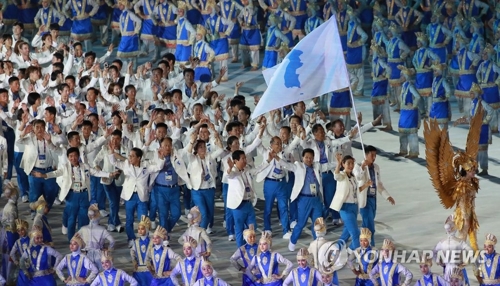 朝鮮半島旗を掲げて入場する南北の選手たち＝１８日、ジャカルタ（聯合ニュース） 
