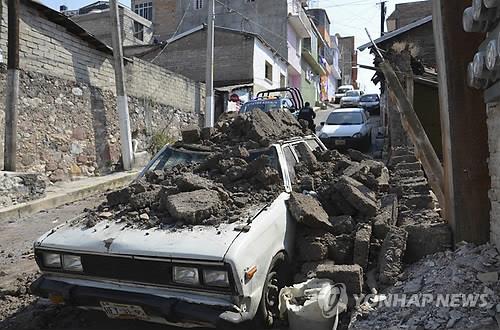 18일(현지시간) 멕시코 중남부 일대에서 발생한 규모 7.2의 지진으로 게레로주의 주도 칠파신고의 한 주택가 외벽이 무너져 주차된 차량이 부숴졌다.(AP=연합뉴스)