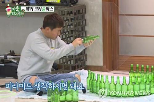 This image captured from SBS TV's reality television show "Mom's Diary -- My Ugly Duckling" shows singer Kim Gun-mo building a Christmas tree out of empty soju bottles. (Yonhap) 